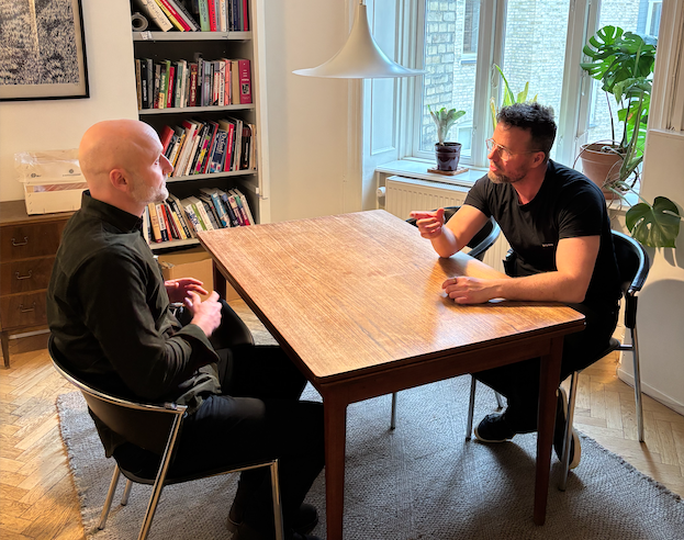 Jesper fra Styrkeleder afholder en styrkebaseret coaching-samtale med en leder over et bord.