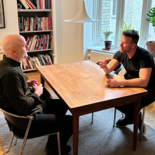 Jesper fra Styrkeleder afholder en styrkebaseret coaching-samtale med en leder over et bord.